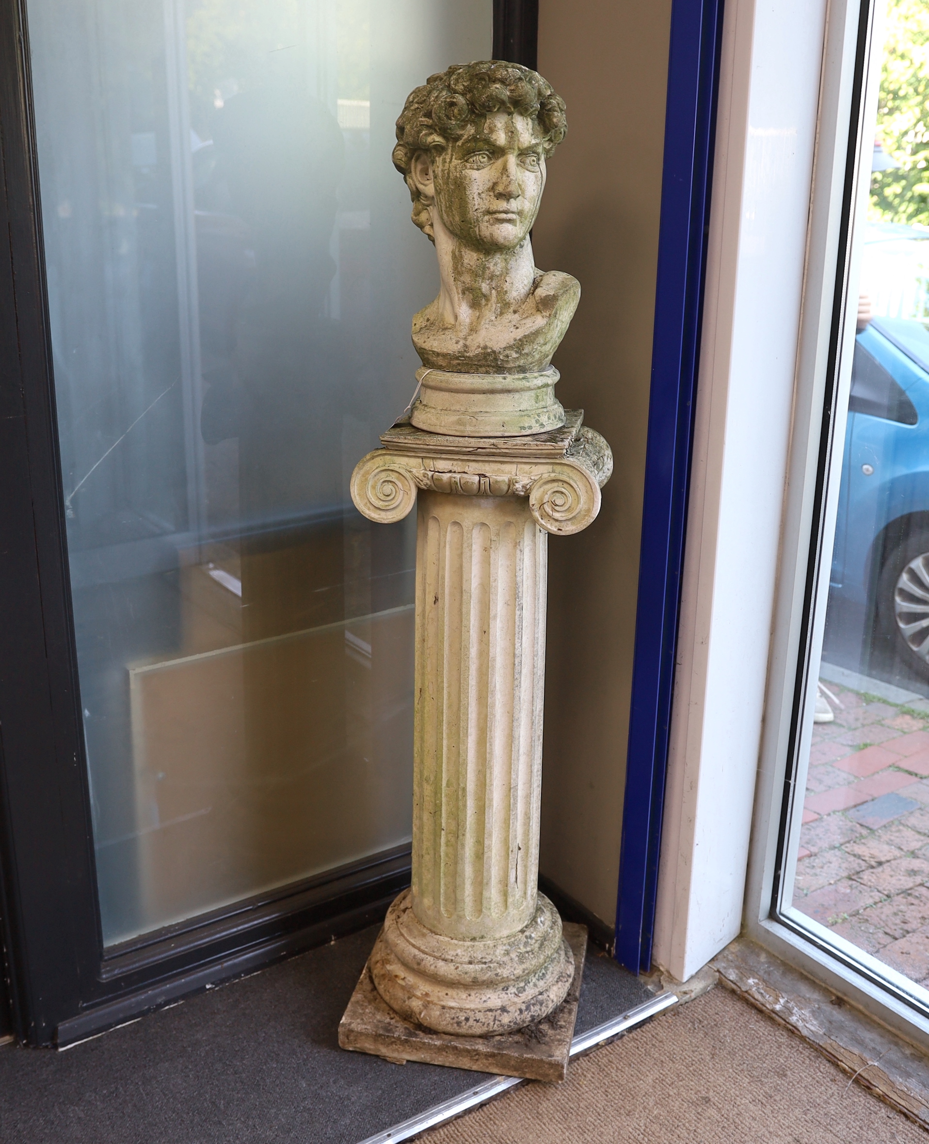 A reconstituted stone bust of David on ionic column pedestal, height 158cm